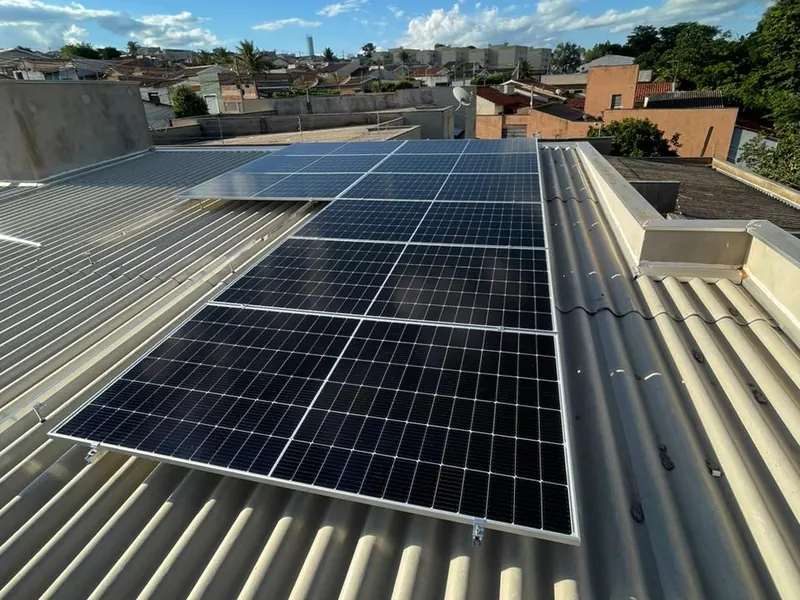 Painel solar instalado em cobertura, com a cidade ao fundo